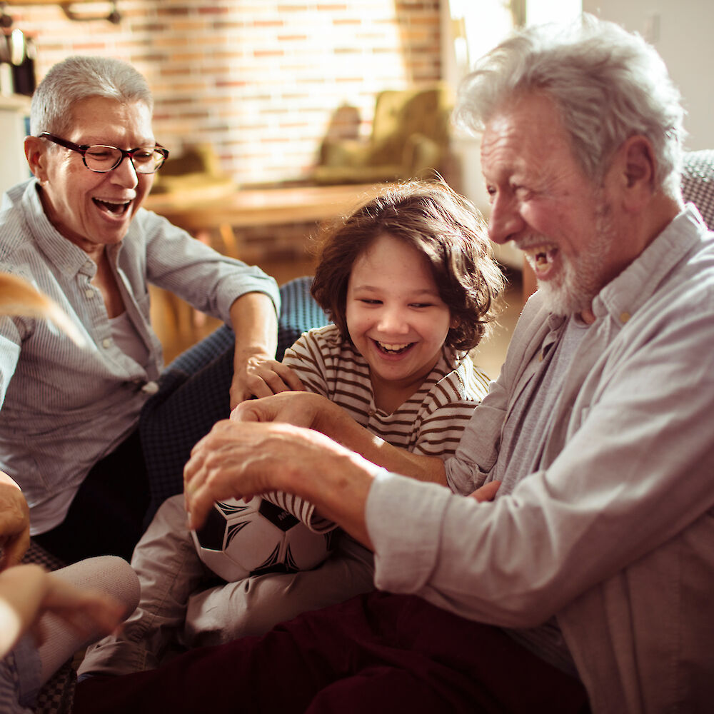 Familienbild, der Opa hält einen Fußball und alle lachen herzlich.