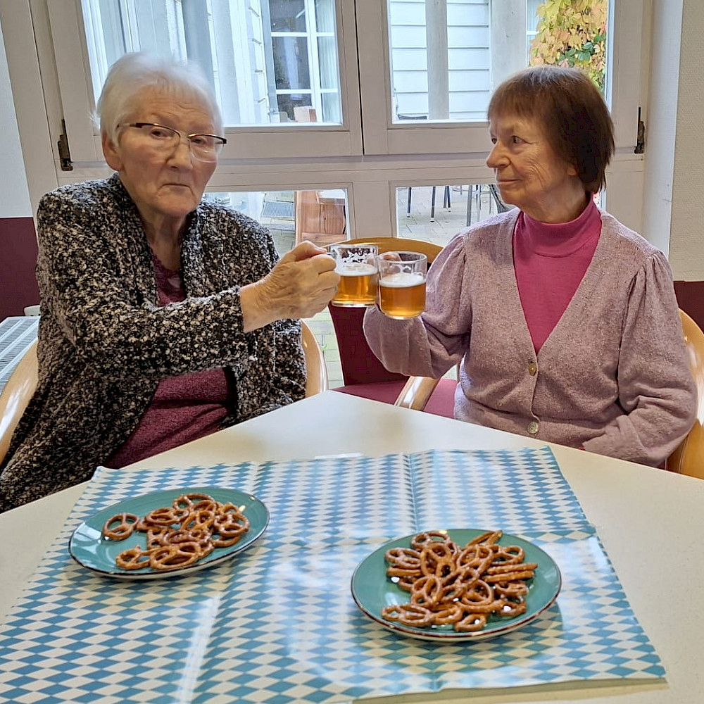 Bewohnerinnen feiern das Oktoberfest. Sie stoßen mit Bier an.